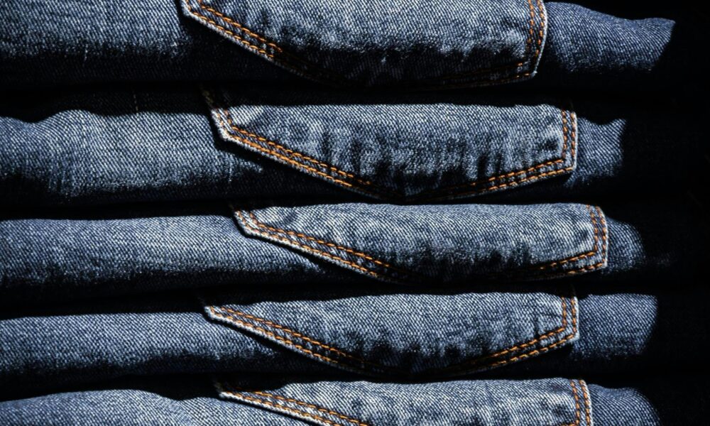 Neatly stacked blue jeans with visible price tag in retail setting.