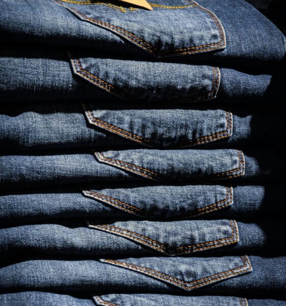 Neatly stacked blue jeans with visible price tag in retail setting.