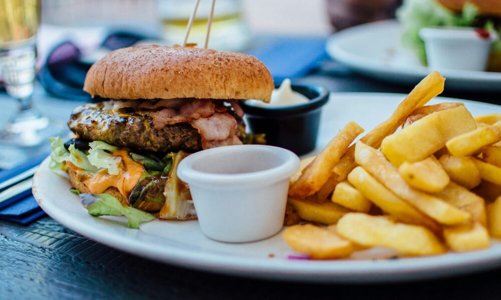 Close-up of a juicy burger and crispy fries served with sauces, perfect for a hearty meal.