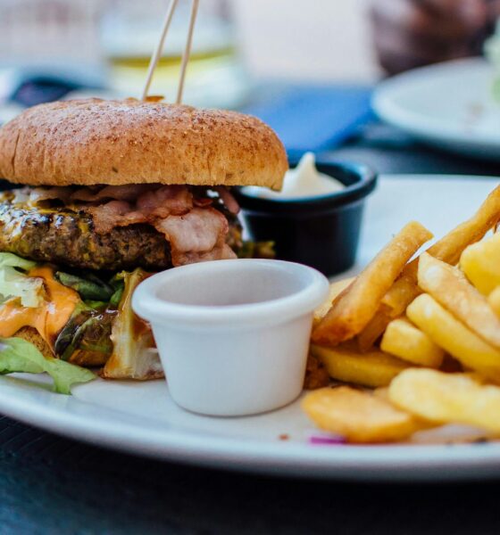 Close-up of a juicy burger and crispy fries served with sauces, perfect for a hearty meal.