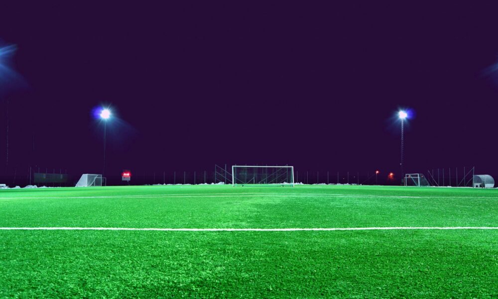 A brightly lit soccer field at night in Norrtälje, Sweden, showcasing green turf and stadium lights.